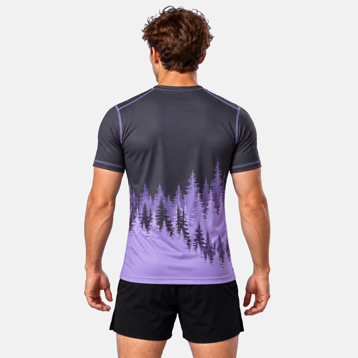 Grafiiditooni ja lavendlivärvi metsasiluetiga lühikeste varrukatega rashguard mehe seljas, tagantvaade.