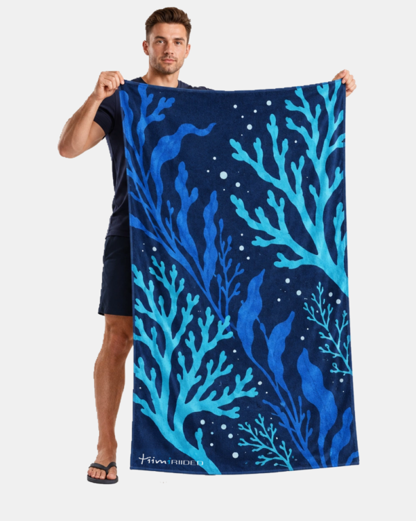 Mees hoiab sinise meretaimemustriga Tiimiriiete rannarätikut mõõduga 100 × 150 cm.